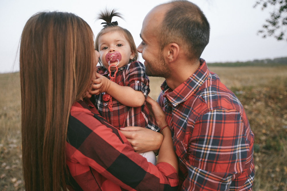 Parents Huging Daughter In A Field