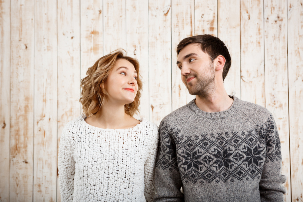 Young Couple Looking At Each Other With Wooden Wall Background