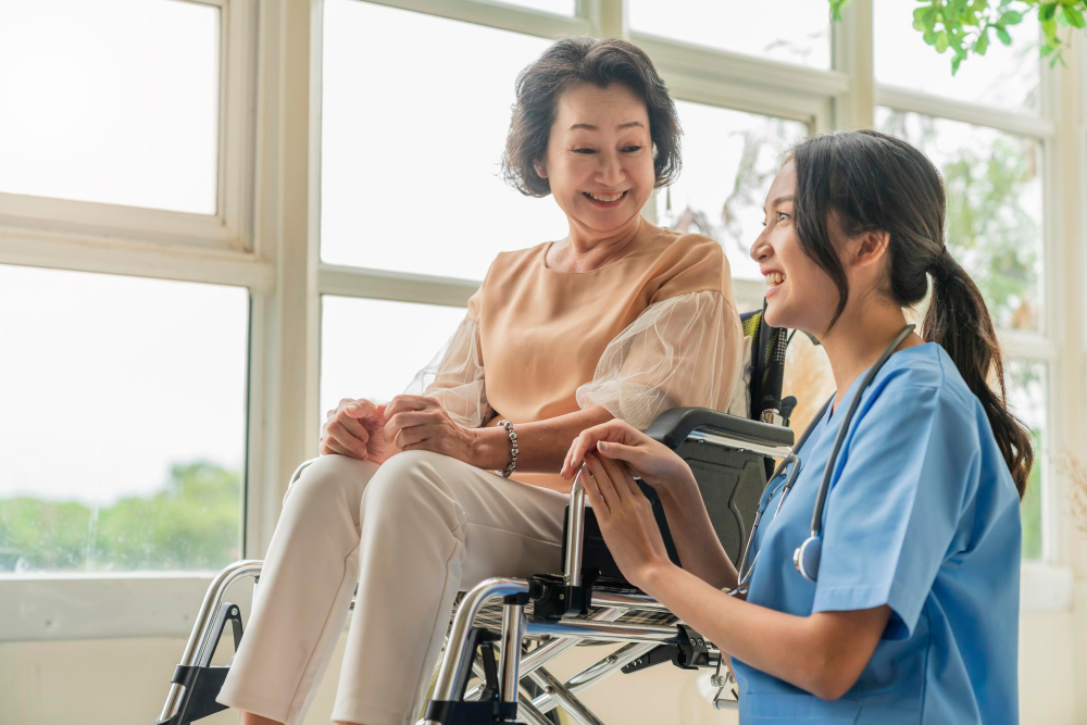 Asian Young Caregiver Caring For Her Elderly Patient In A Wheelchair