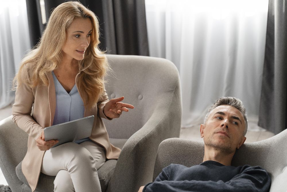 Woman Therapist Talking To Man Laying On Couch