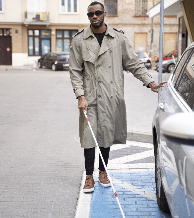 Blind Man Walking With Cane Next To Parked Car